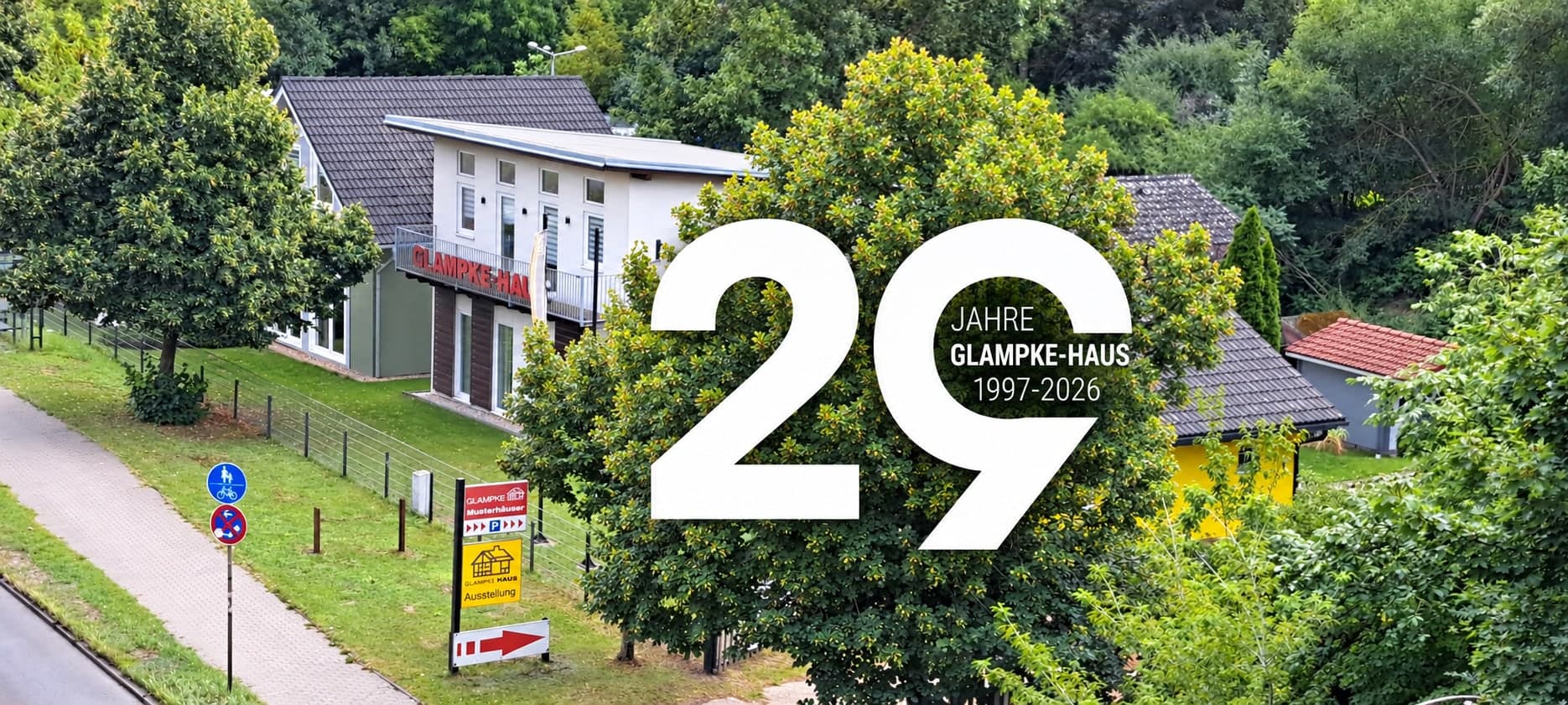 Luftaufnahme des Musterhausparks an der B1 mit dem Betriebsgebäude und den Musterhäusern, darüber die Zahl 29 mit der Zeile Jahre Glampke-Haus 1997 bis 2026