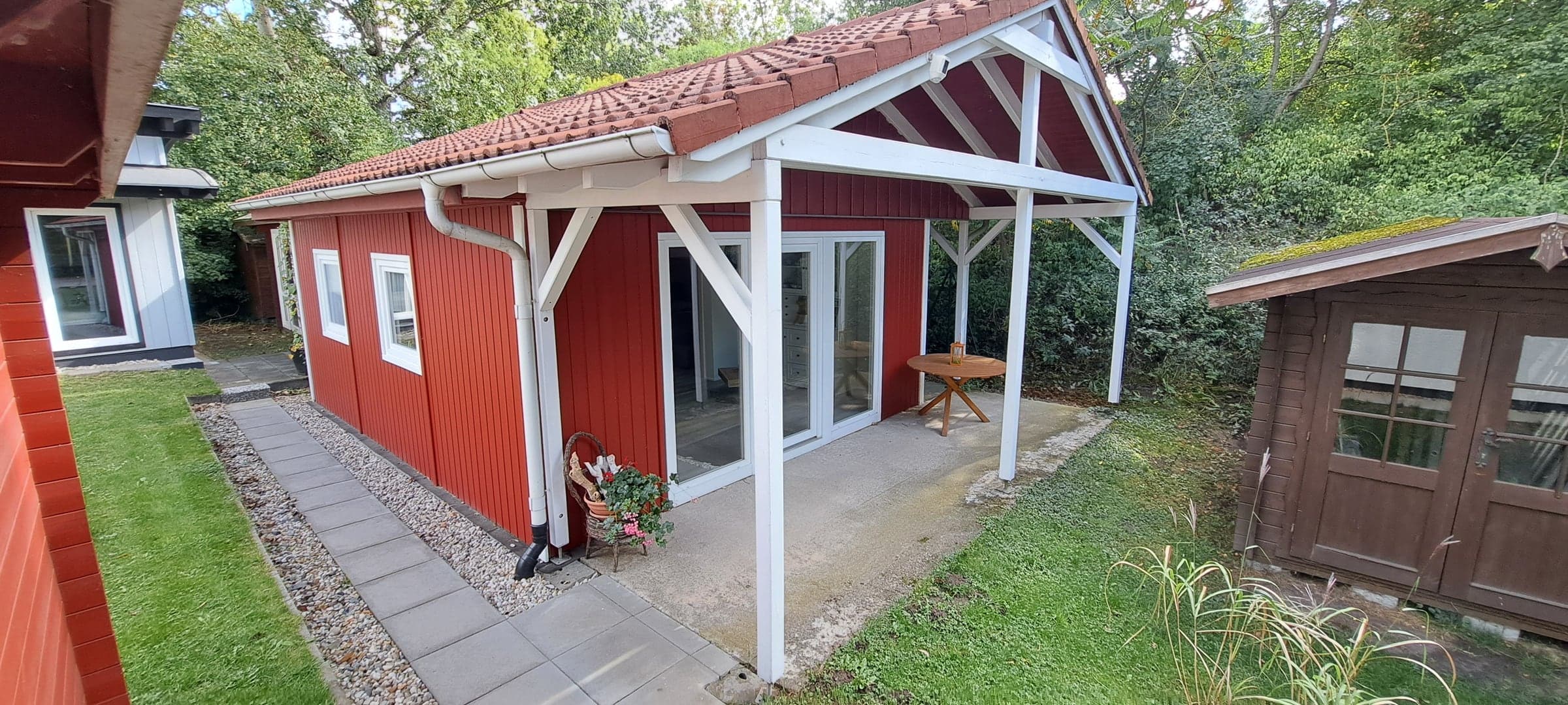Rotes Ferienhaus mit weißer Pergola und Terrasse