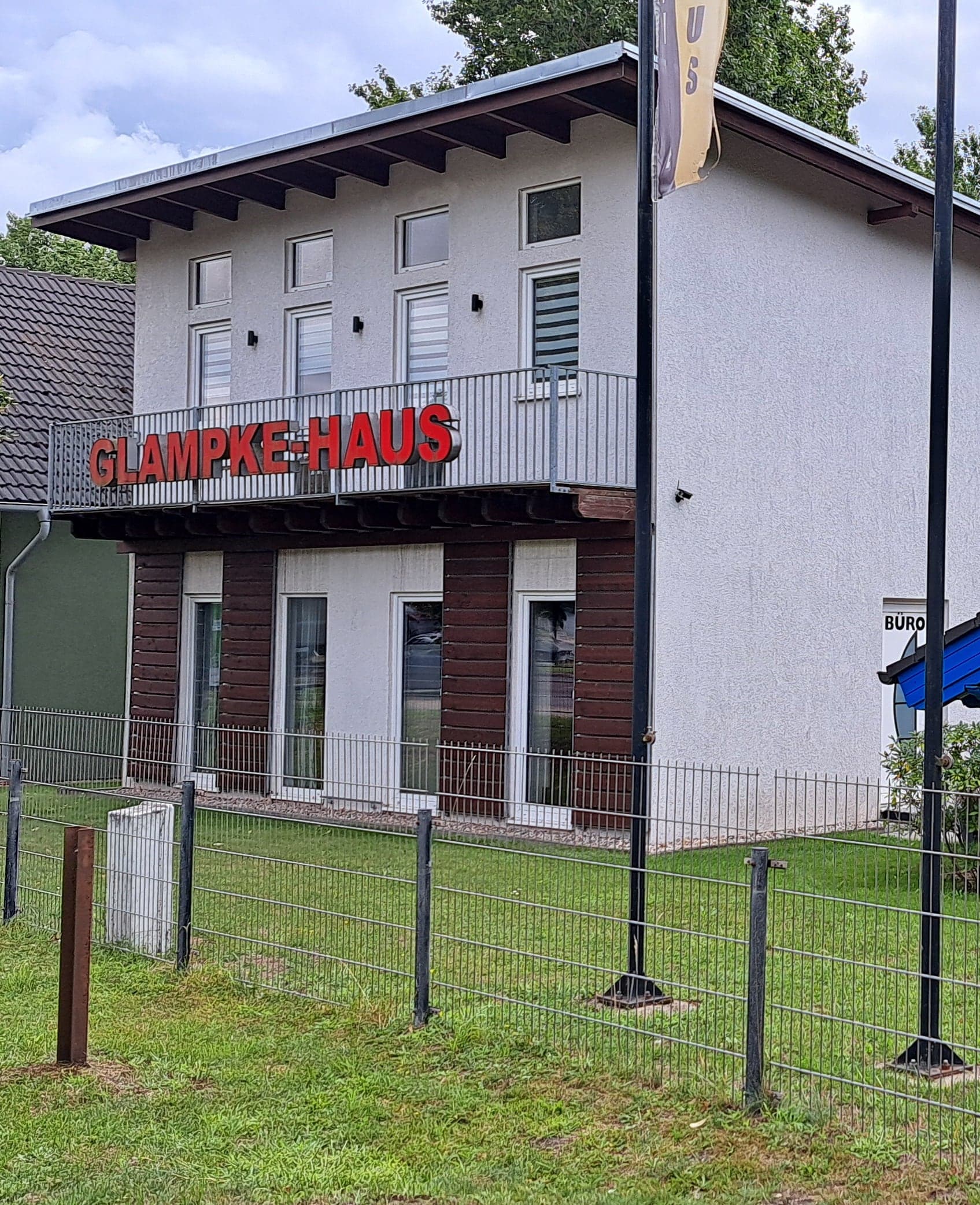 Betriebsgebäude von Glampke-Haus mit rotem Schriftzug, daneben ein gelbes Musterhaus