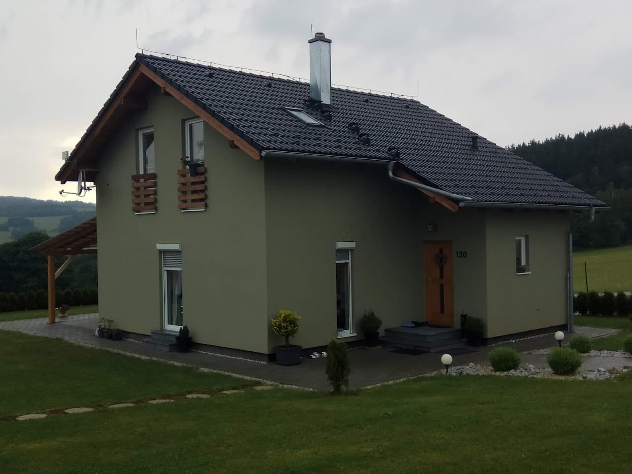 Olivgrünes Haus mit Blumenkästen, Vordach und frisch gemähtem Rasen
