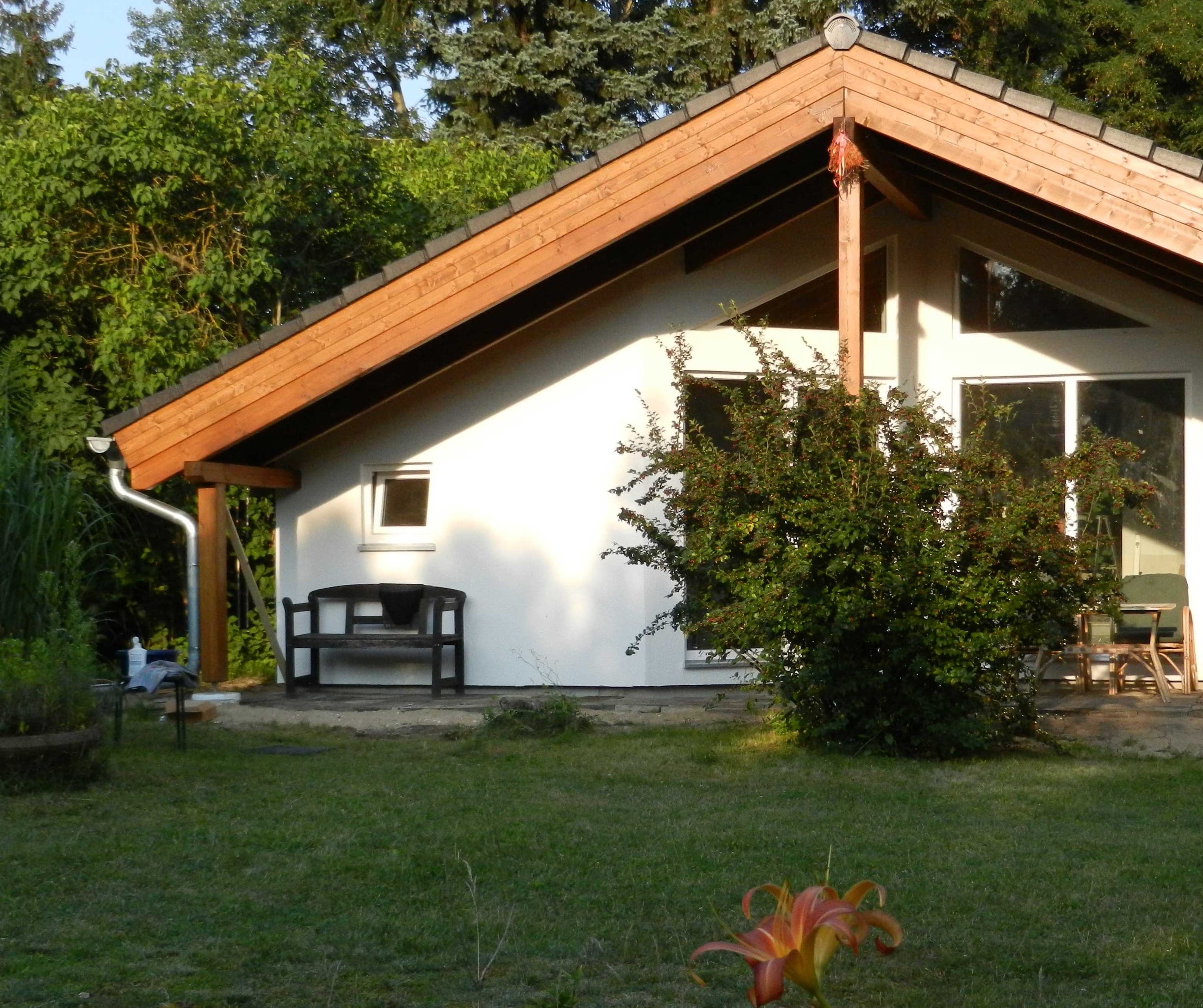 Holzhaus im Abendlicht, Giebel und Fenster warm beleuchtet